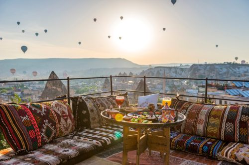 Traditional turkish breakfast with Cappadocia view and flying balloons on the background. 