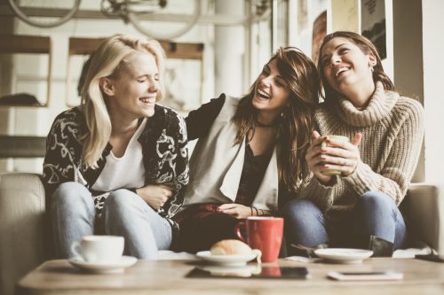 Women laughing together drinking coffee.