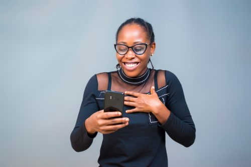 woman laughing while looking at her phone