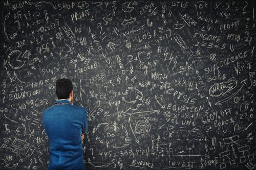 man facing a blackboard full of math problems