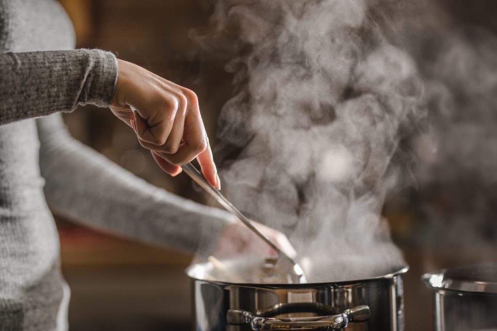 Closeup of someone stirring a pot of soup on the stove