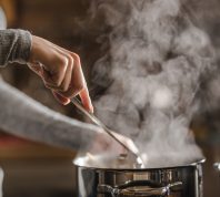 Closeup of someone stirring a pot of soup on the stove