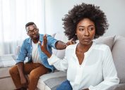 Woman pushing man aside during argument on the couch