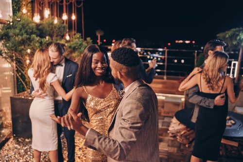 A beautiful, young couple dancing at a rooftop party at night