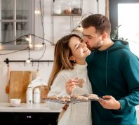 Young couple hugging while baking cookies in the kitchen