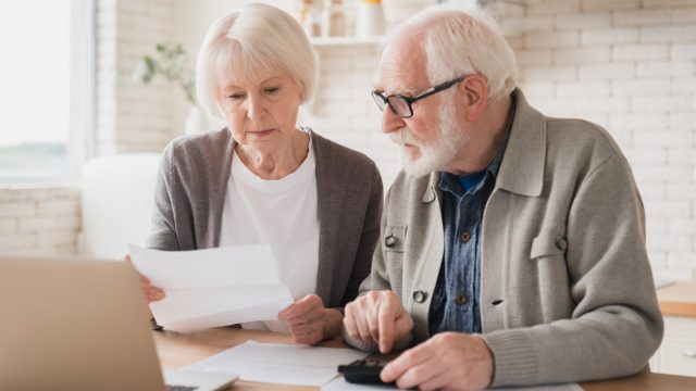 A senior couple sitting together with a laptop and calculator paying bills