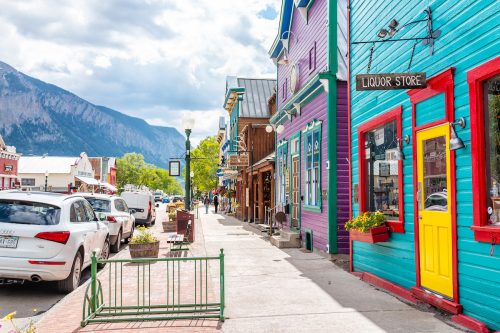 Elk Street in Crested Butte, Colorado, lined with colorful wooden buildings with the Rocky Mountains in the background.