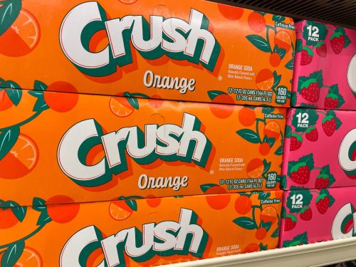 Close up of boxes of Orange Crush soda on a store shelf.