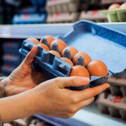 A closeup of a person inspecting a carton of eggs in the supermarket