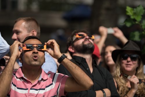 A group of people watching a solar eclipse using special glasses