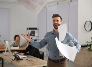 A happy young man who just quit his job throwing papers in the air.
