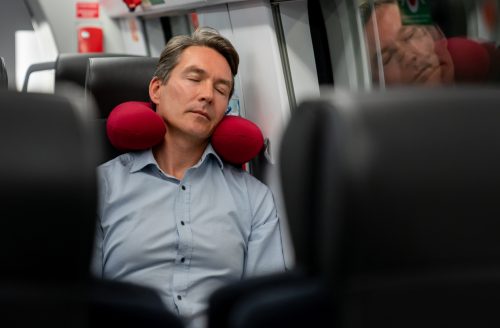 Man traveling and using a neck pillow.