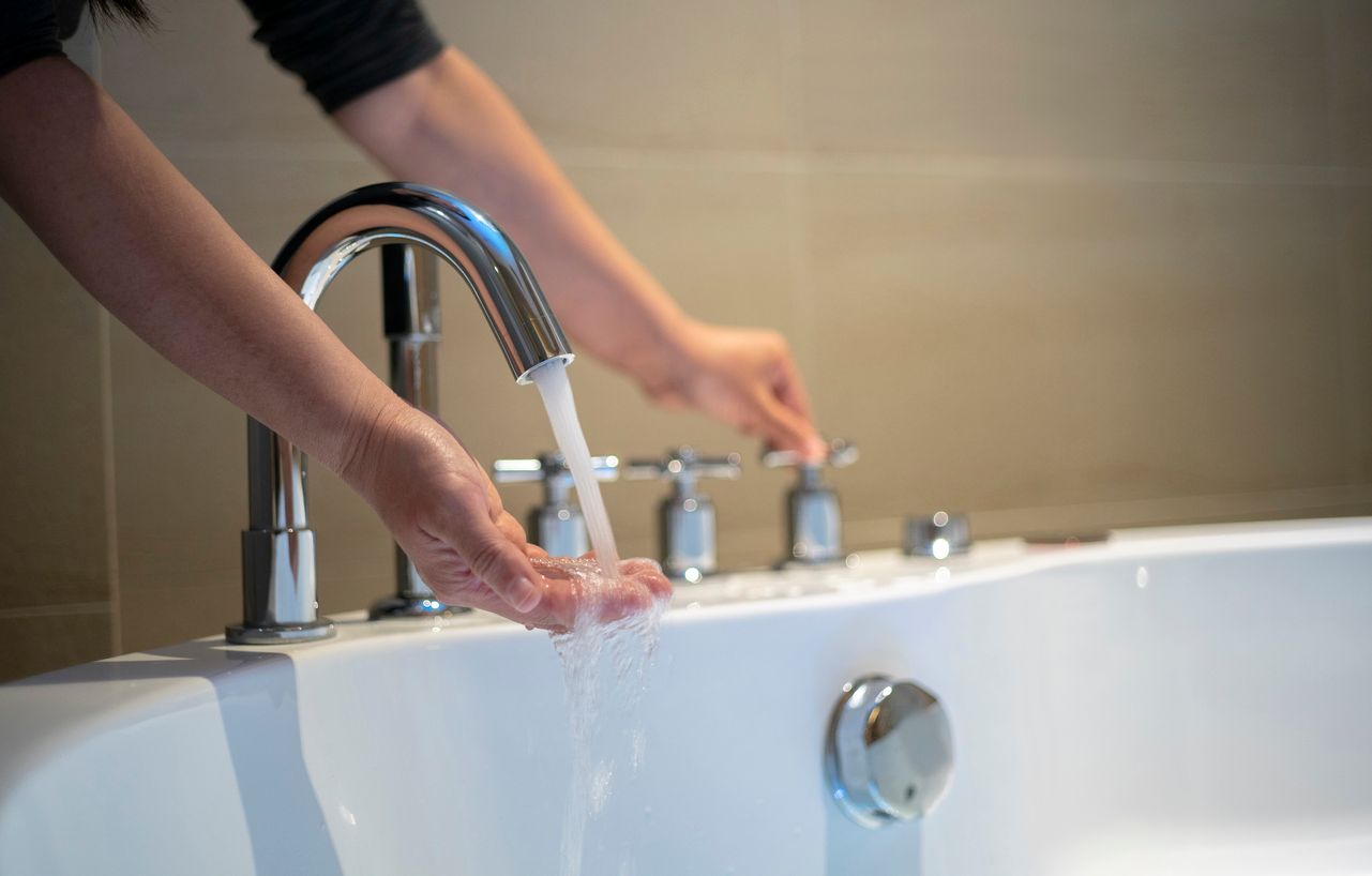 Person turning on water in bathtub.