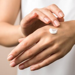 Woman putting moisturizer on her hand.