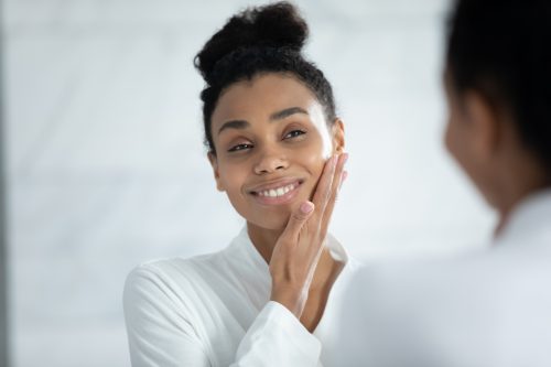Woman applying eye cream in the mirror.
