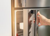 Hand opening a refrigerator door.