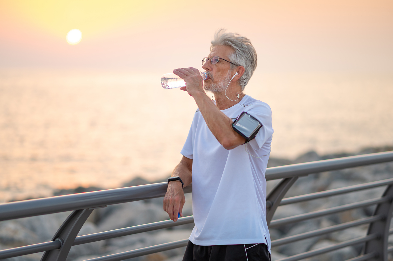 Mature man drinking water outdoors.