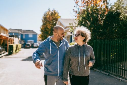 Couple walking down a street together in a residential neighborhood.
