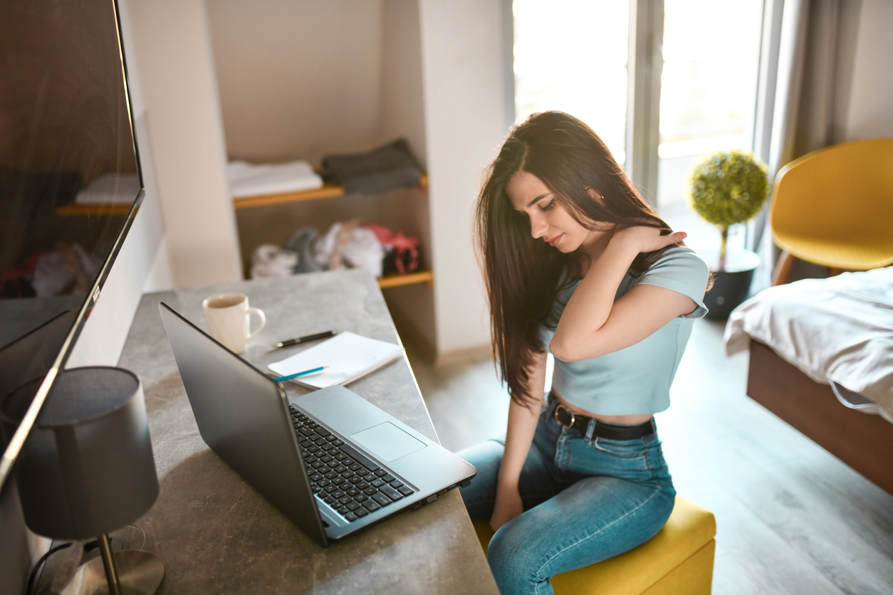 امرأة تجلس مع كمبيوتر محمول يفرك كتفها.