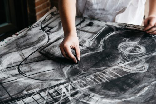 Young female artist painting with charcoal on paper