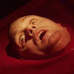 A close up image of actor Alexander Skarsgård looking up from a red pool