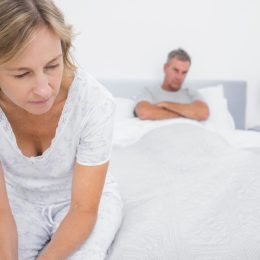 Couple sitting on opposite ends of bed