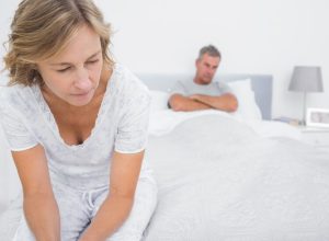 Couple sitting on opposite ends of bed