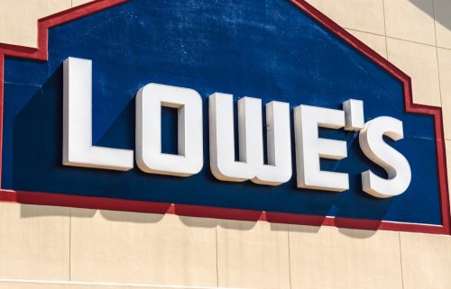 Horizontal, medium closeup of "Lowe's" exterior facade brand and logo signage on a bright sunny day.