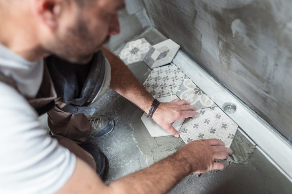 A builder installing new tiles in a bathroom