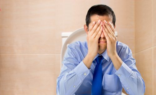 businessman sitting on the toilet with hemorrhoids