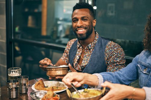young black man eating indian food