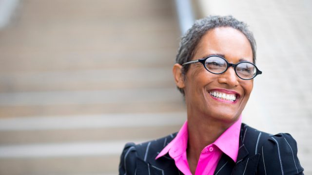 An older businesswoman with short gray hair and a magenta shirt under navy blazer