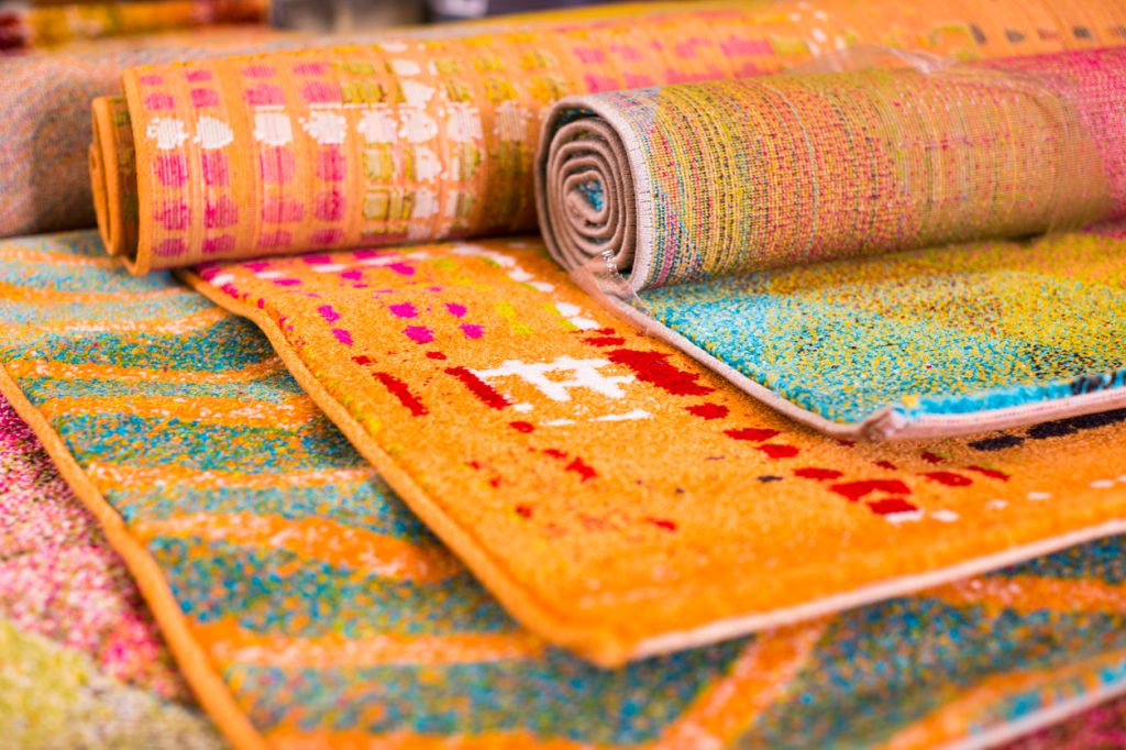 A variety of brightly colored rugs rolled up on display next to each other