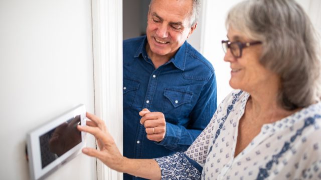 Senior man explaining to his wife how to set burglar alarm at home