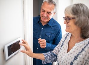 Senior man explaining to his wife how to set burglar alarm at home