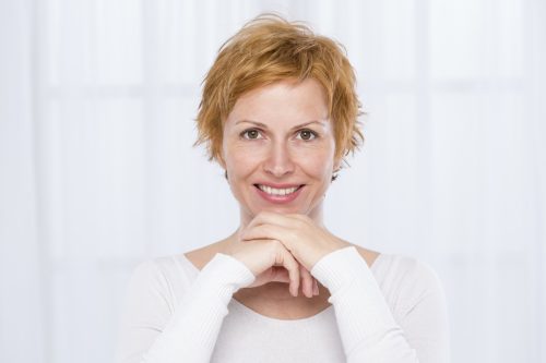 mature woman with short red hair wearing a white long-sleeved t-shirt
