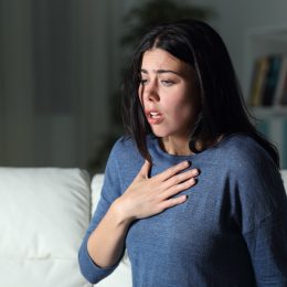 Woman suffering an anxiety attack alone in the night on a couch at home