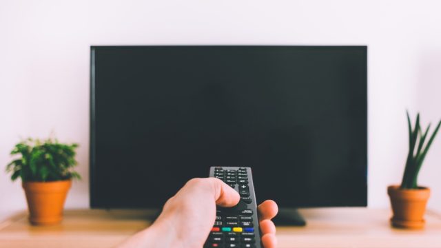 person using remote on tv
