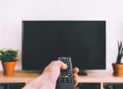 person using remote on tv