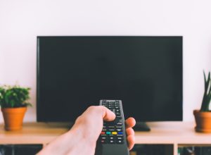 person using remote on tv