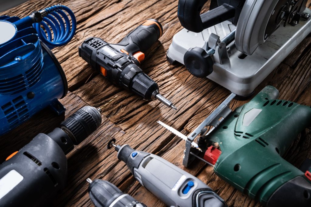 Power tools on a table, including a jigsaw, drill, and nail gun