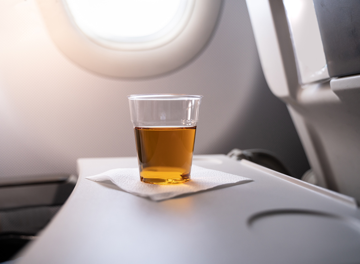 glass of brown liquor on an airplane tray table
