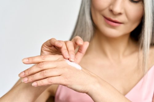 older woman applying lotion to hands
