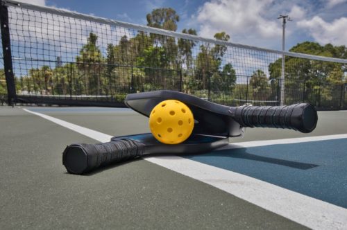 pickleball paddles and ball on court