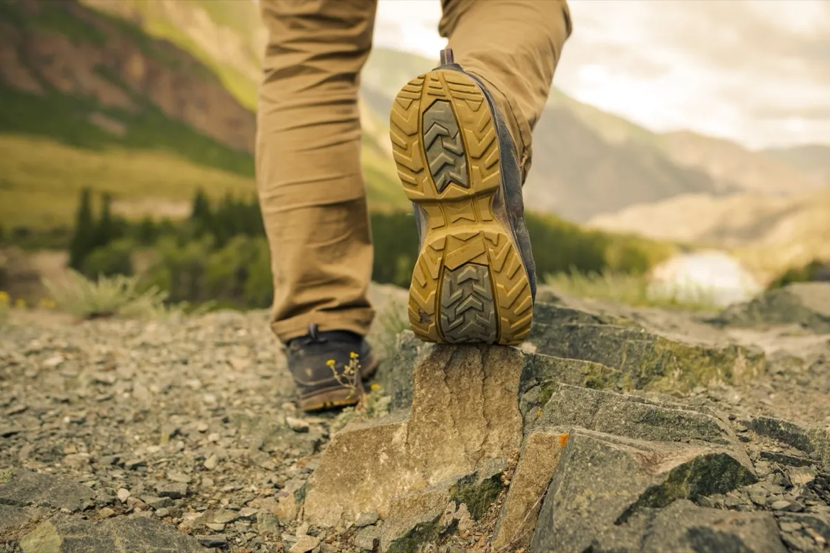 close up of man wearing hiking boots on mountains