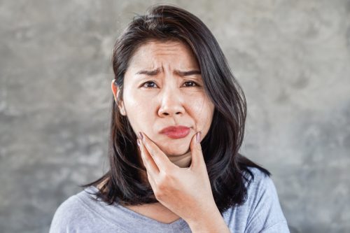 Asian woman having problem with Bell's Palsy/Facial Palsy, hand holding her face