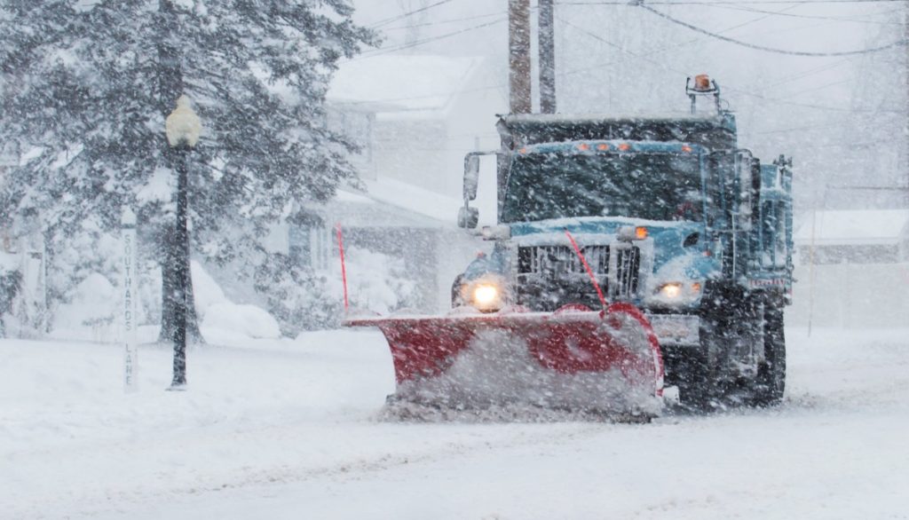 Snow plow is plowing the roads during a storm