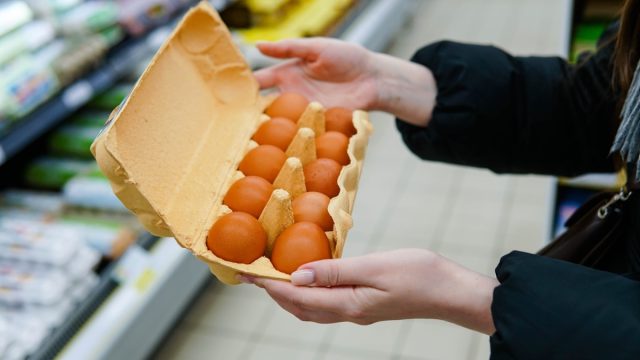 Woman chooses chicken eggs in a grocery store. Close up.