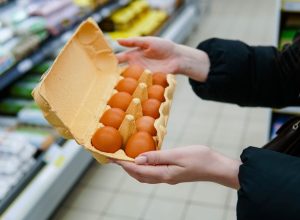 Woman chooses chicken eggs in a grocery store. Close up.
