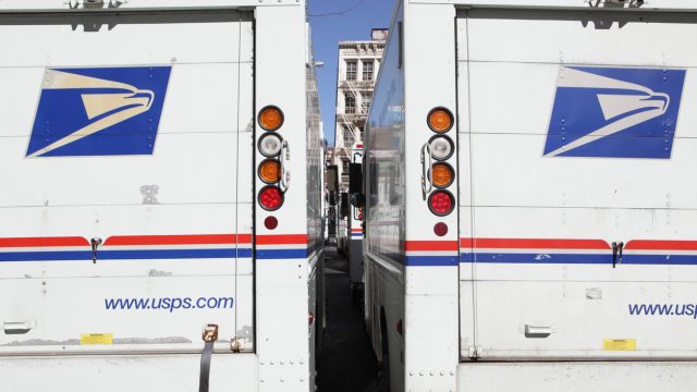 The rear doors of two USPS mail delivery trucks